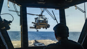 A U.S. Sailor observes as an MH-60R Sea Hawk, assigned to Helicopter Maritime Strike Squadron (HSM) 51, taking off from the flight deck of Arleigh Burke-class guided-missile destroyer USS Rafael Peralta (DDG 115) as it patrols the Arabian Sea enforcing a maritime blockade against ships entering or exiting Iranian ports and coastal areas, May 12, 2026. Rafael Peralta is deployed to the U.S. 5th Fleet area of operations to support maritime security and stability in the Middle East. (U.S. Navy photo)